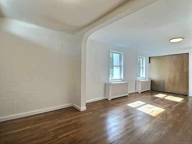 141 Arcadia Ave, Bridgeport, CT 06604 - unfurnished room with arched walkways, hardwood / wood-style flooring, baseboards, and radiator