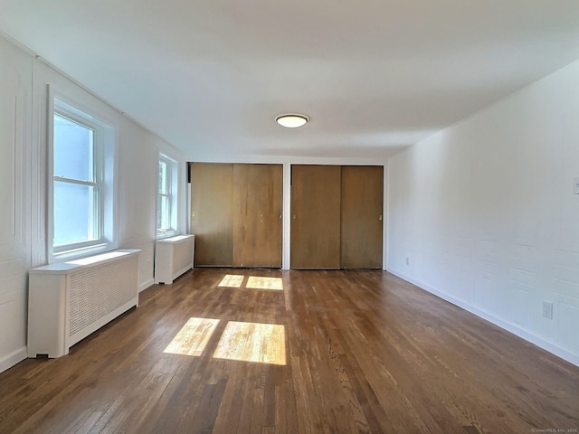 141 Arcadia Ave, Bridgeport, CT 06604 - unfurnished bedroom featuring baseboards, dark wood finished floors, multiple closets, and radiator heating unit