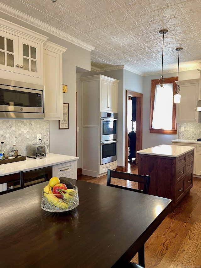 kitchen featuring an ornate ceiling, stainless steel appliances, dark wood-style flooring, and tasteful backsplash