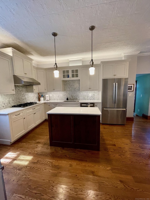 kitchen featuring gas cooktop, light countertops, freestanding refrigerator, under cabinet range hood, and a kitchen island