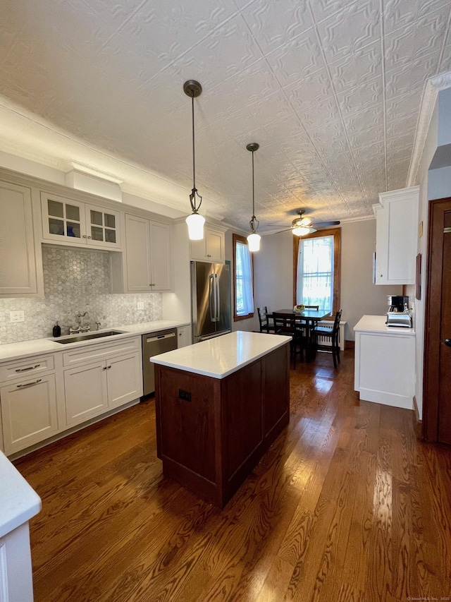 kitchen with appliances with stainless steel finishes, a sink, light countertops, white cabinetry, and dark wood-type flooring