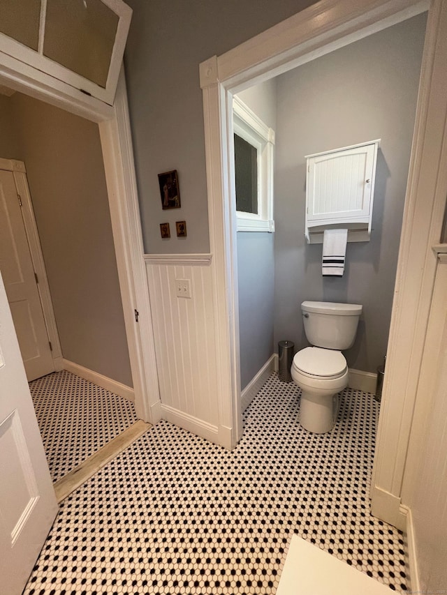 bathroom featuring baseboards, a wainscoted wall, and toilet