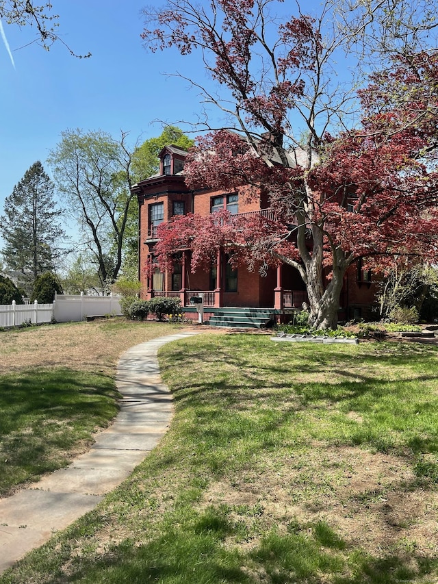 view of front of house featuring a front lawn, fence, and covered porch