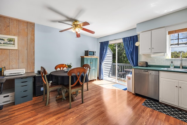 dining area featuring light wood-type flooring, wooden walls, and ceiling fan