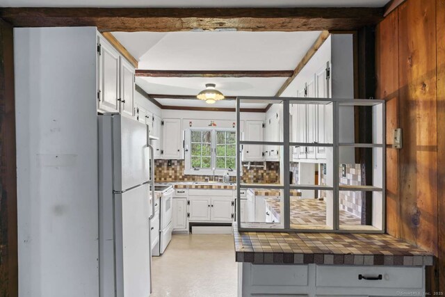 kitchen featuring white appliances, white cabinetry, a sink, and tasteful backsplash