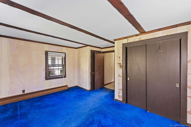 unfurnished bedroom featuring carpet floors, beamed ceiling, and a baseboard heating unit