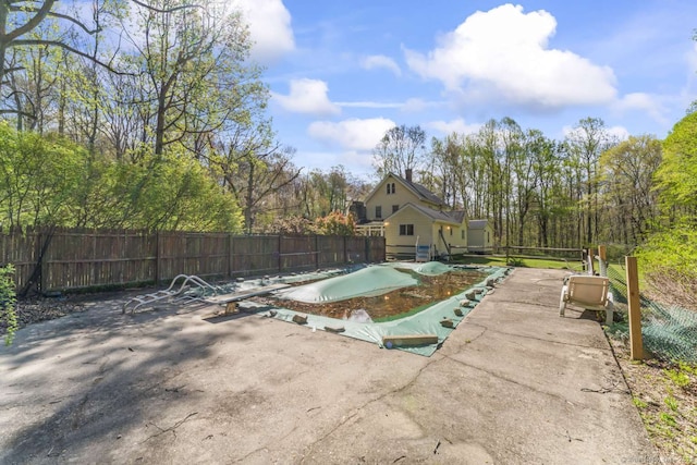 view of pool with a patio, fence, and a diving board
