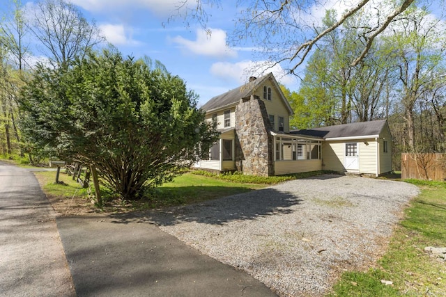 view of home's exterior featuring a chimney, fence, a yard, and gravel driveway