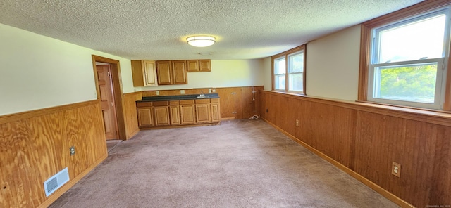 116 Aimes Dr, West Haven, CT 06516 - kitchen featuring visible vents, brown cabinetry, wainscoting, wooden walls, and a textured ceiling