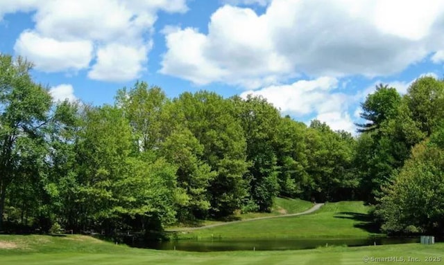 view of home's community featuring a lawn, a water view, and view of golf course