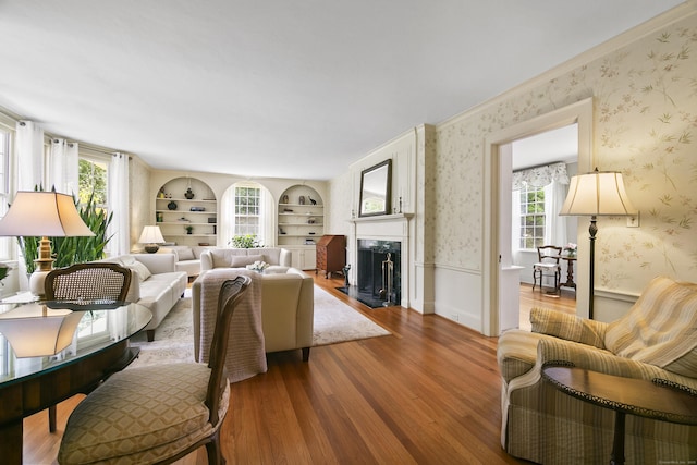 living area featuring wood finished floors, a fireplace, and wallpapered walls