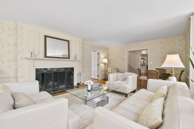 living area featuring crown molding, light wood-style floors, a premium fireplace, a wainscoted wall, and wallpapered walls