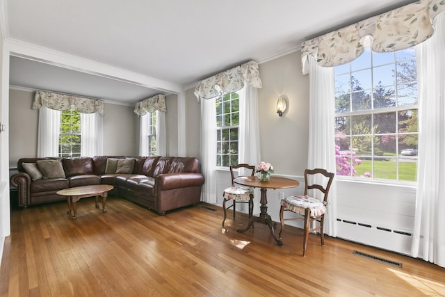 living area with light wood-style floors, crown molding, plenty of natural light, and visible vents