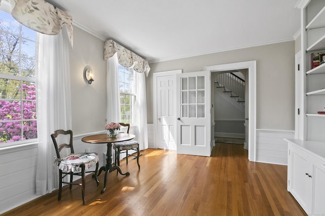 interior space with ornamental molding, wainscoting, wood finished floors, and stairway