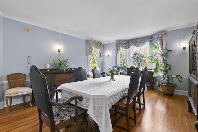 dining area featuring crown molding, baseboards, and wood finished floors