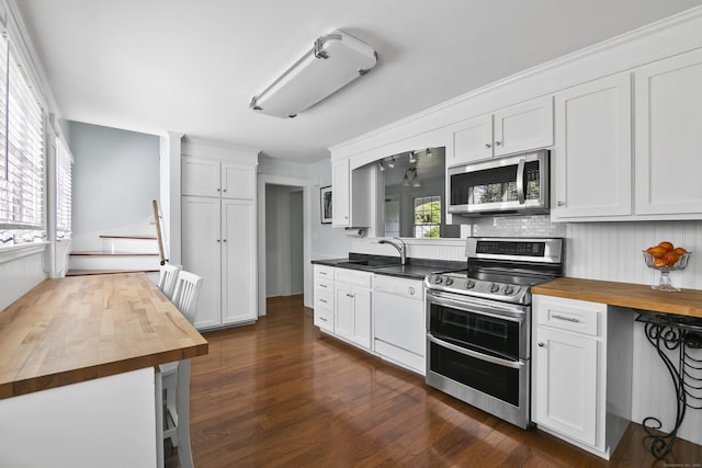 kitchen with a sink, appliances with stainless steel finishes, white cabinets, and butcher block countertops