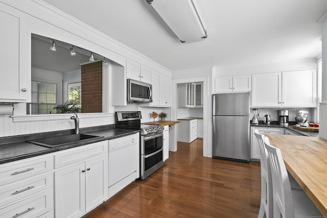 kitchen featuring wooden counters, a sink, white cabinets, stainless steel appliances, and dark wood-type flooring