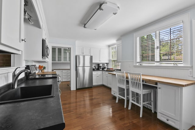 kitchen with dark wood-style floors, white cabinets, a sink, wood counters, and appliances with stainless steel finishes