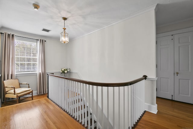 corridor with ornamental molding, hardwood / wood-style floors, and an upstairs landing