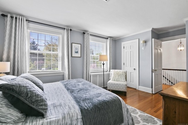 bedroom with baseboards, ornamental molding, and wood finished floors