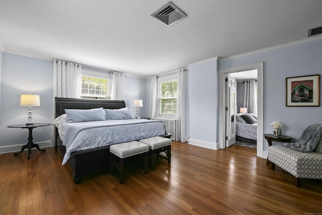 bedroom with baseboards, ornamental molding, wood finished floors, and visible vents