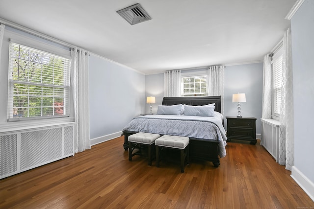bedroom with visible vents, crown molding, wood finished floors, baseboards, and radiator