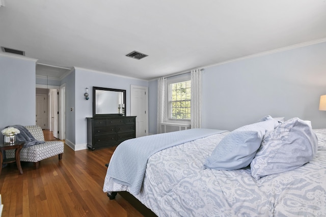 bedroom featuring ornamental molding, attic access, wood finished floors, and visible vents