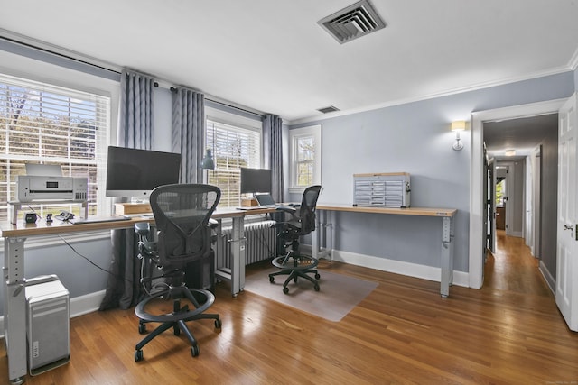 home office with baseboards, ornamental molding, wood finished floors, and visible vents