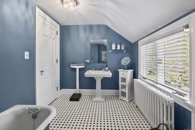 bathroom featuring a soaking tub, baseboards, radiator heating unit, and lofted ceiling