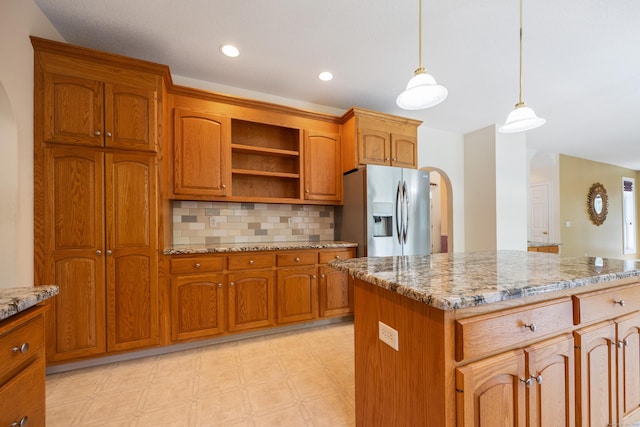 85 Chippenwood Ln, Bristol, CT 06010 - kitchen featuring stainless steel fridge, arched walkways, brown cabinetry, and light stone countertops