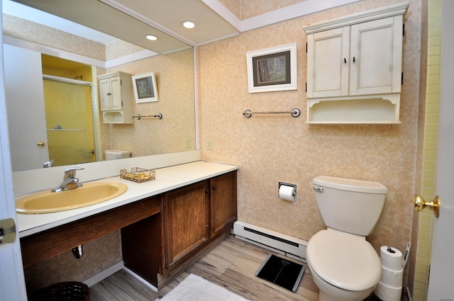 bathroom with toilet, a baseboard heating unit, wood finished floors, a shower with door, and vanity