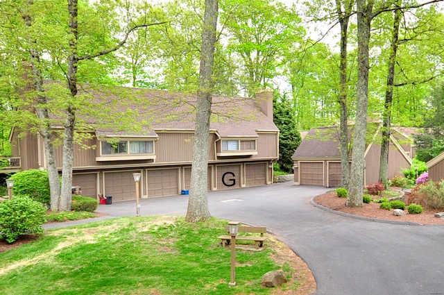 view of front of home featuring a chimney, driveway, a garage, and roof with shingles