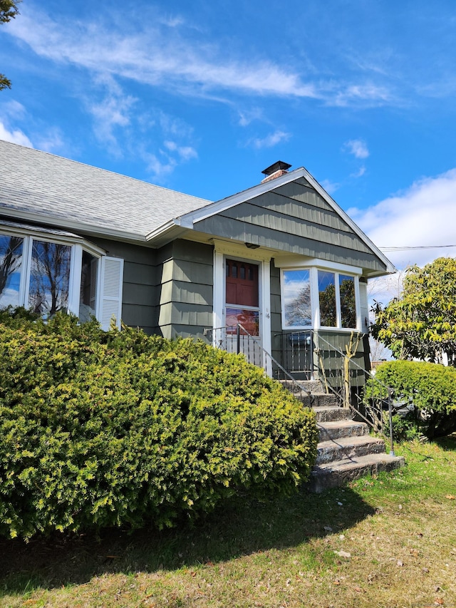 view of front of home with a shingled roof and a chimney