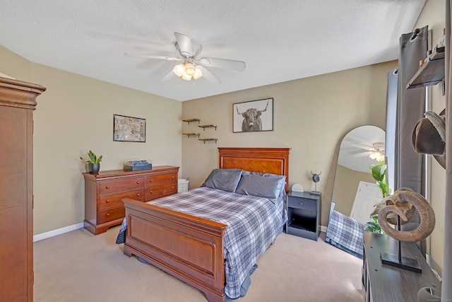 bedroom featuring baseboards, ceiling fan, a textured ceiling, and light colored carpet