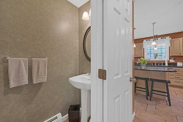 bathroom with a sink, tile patterned floors, baseboard heating, and wallpapered walls