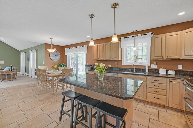 kitchen featuring a center island, a sink, a kitchen breakfast bar, and light brown cabinets