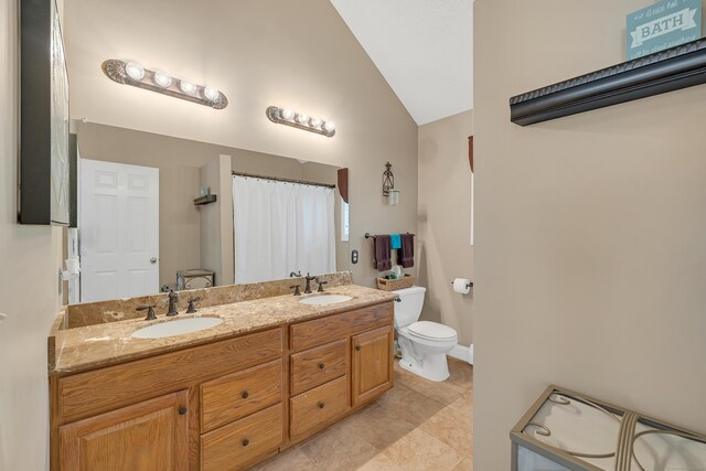 bathroom with double vanity, toilet, vaulted ceiling, and a sink