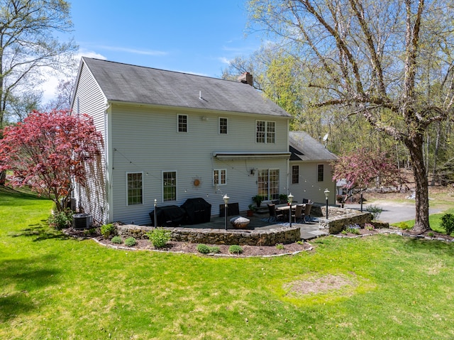 rear view of house featuring a patio, a lawn, a chimney, and cooling unit