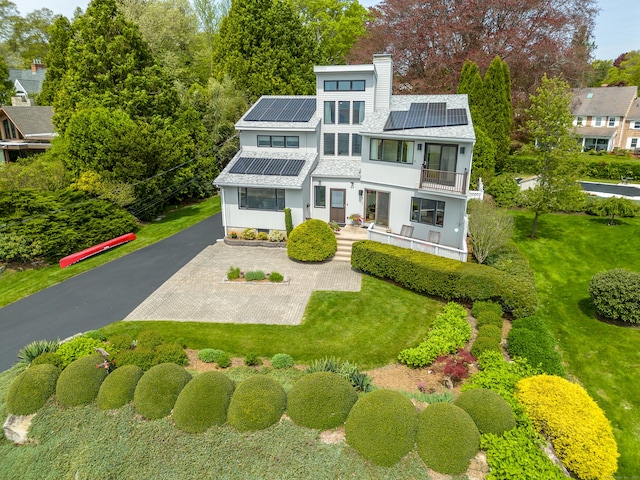 919 Pequot Ave, New London, CT 06320 - view of front of home with a balcony, solar panels, a chimney, and a front yard