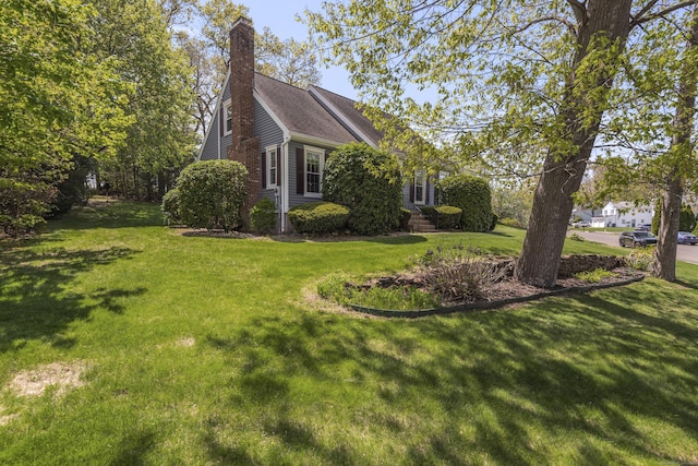 view of side of home featuring a chimney and a lawn