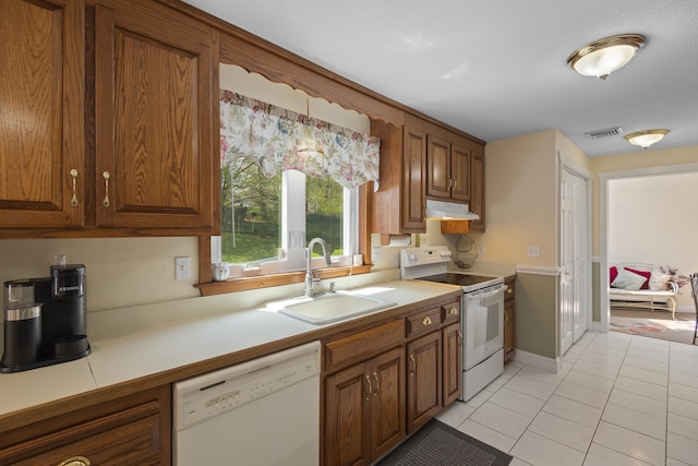 kitchen with light tile patterned floors, a sink, visible vents, white appliances, and under cabinet range hood