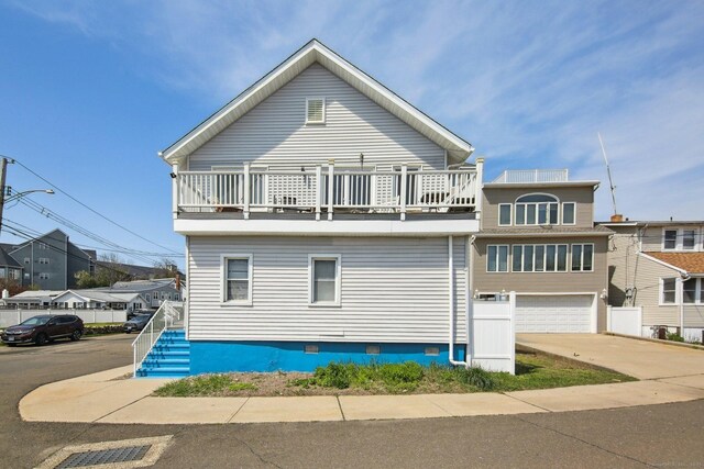 back of property featuring a balcony, crawl space, a garage, and concrete driveway