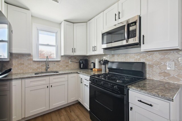kitchen featuring black gas stove, stainless steel microwave, a sink, white cabinetry, and dark wood-style flooring