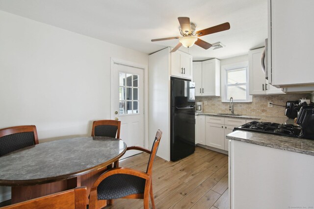 kitchen featuring freestanding refrigerator, a sink, range, light wood-type flooring, and decorative backsplash