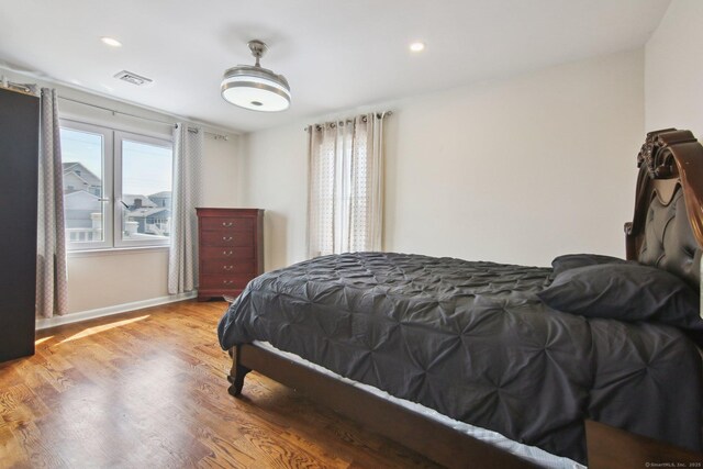 bedroom with wood finished floors, baseboards, and recessed lighting