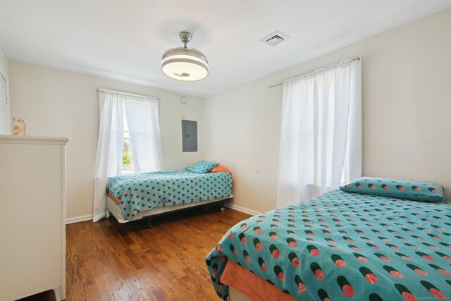 bedroom featuring wood finished floors, baseboards, and electric panel