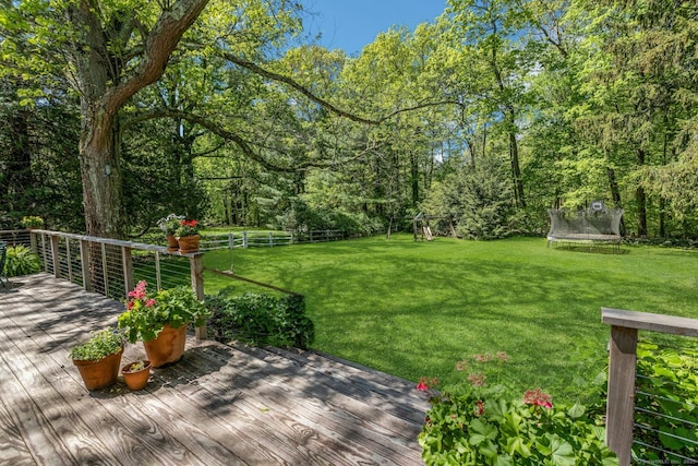 view of yard with a trampoline, a deck, and a playground