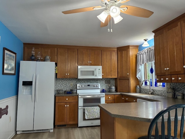 kitchen featuring white appliances, light wood finished floors, ceiling fan, a sink, and brown cabinets