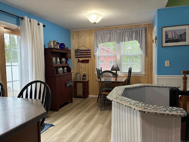 dining area featuring light wood finished floors and wood walls