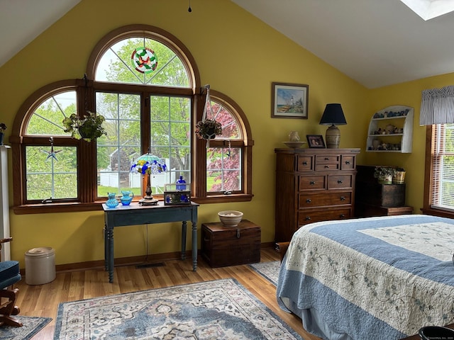 bedroom featuring vaulted ceiling, multiple windows, and wood finished floors